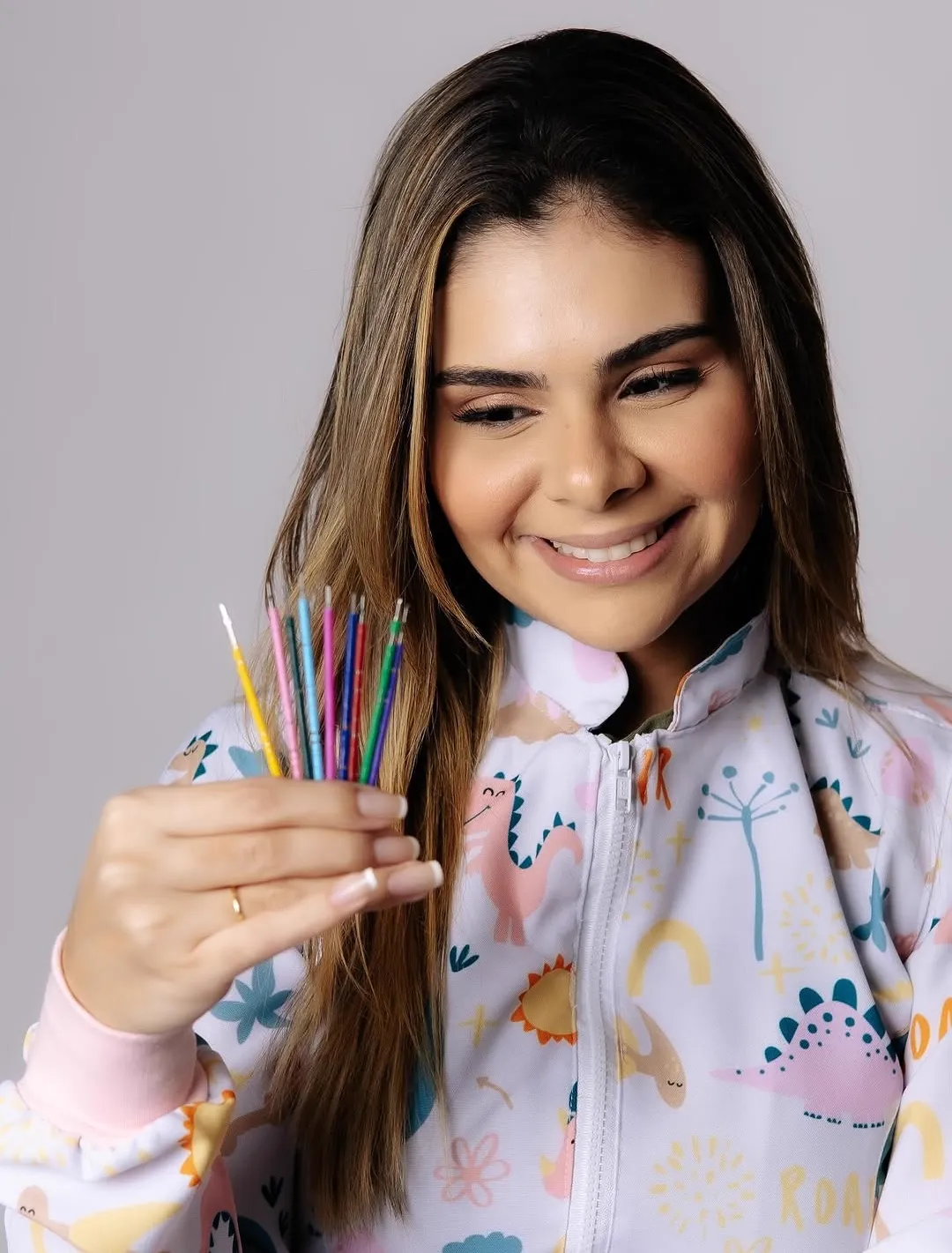 A Dra. Desirée segura um punhado de escovas de dente coloridas.